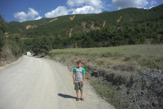 Bild: Junge auf unbefestigter Straße vor grünen Bergen