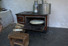 Bild: Ofen mit traditionellem Brot, Holzschemel und Feuerholz